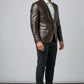 Model wearing a Scarlett Stitch dark brown leather blazer with a white shirt and dark trousers in a studio setting.