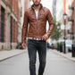 Man wearing a brown Scarlett Stitch faux leather jacket with a stand collar, white t-shirt, and dark jeans on a street