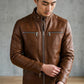 Scarlett Stitch men's brown leather jacket with a stand-up collar, metal zippers, and chest pockets on a male model.