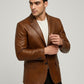 Man wearing a Scarlett Stitch cognac brown leather blazer with notch lapels and a single-button closure.