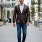 Man wearing a Scarlett Stitch dark brown leather blazer with a white shirt and jeans on a city street.