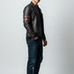 Scarlett Stitch men's black leather racer jacket with red sleeve stripes, worn by a model with jeans and white sneakers.