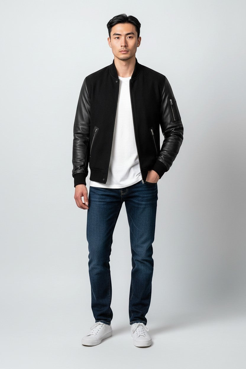 Scarlett Stitch Men's black bomber jacket with genuine leather sleeves, ribbed collar, cuffs, and hem. Features zippered pockets.