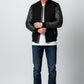 Scarlett Stitch Men's black bomber jacket with genuine leather sleeves, ribbed collar, cuffs, and hem. Features zippered pockets.