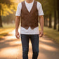 Scarlett Stitch Men's distressed brown leather vest with V-neck, button front, and flap pockets, worn over a white t-shirt.