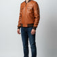 Scarlett Stitch Men's tan faux leather bomber jacket with ribbed collar, cuffs, hem, and dual chest pockets.