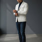 Man wearing a Scarlett Stitch off-white leather blazer with a dark shirt and jeans in a modern studio setting.