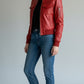 Scarlett Stitch red leather bomber jacket with zippered pockets and ribbed trim, worn by a woman in jeans.