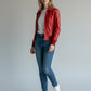 Scarlett Stitch women's red leather bomber jacket with folded collar, zip-front, and ribbed cuffs. Model wears jeans and white sneakers.