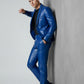 Man wearing a royal blue Scarlett Stitch faux leather suit jacket and matching trousers against a grey wall.