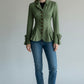 Scarlett Stitch sage green tailored peplum jacket with button detail and bow cuffs, worn by a model with jeans.