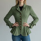 Scarlett Stitch sage green tailored peplum jacket with button detail and bow cuffs, worn by a model with blue jeans.