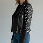 Model wearing a Scarlett Stitch black leather biker jacket with silver stud embellishments on sleeves and shoulders.