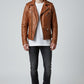 Model wearing a Scarlett Stitch tan leather biker jacket with asymmetrical zip, notched lapels, and waist belt.