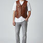 Model wearing a Scarlett Stitch tan leather vest with button front, utility pockets, and white t-shirt over grey jeans.