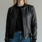 Scarlett Stitch women's black faux leather bomber jacket with ribbed collar, cuffs, and hem. Features full-zip front and zippered pockets.