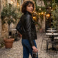 Scarlett Stitch Women's black faux leather moto jacket with zippered pockets and snap collar. Model wears jeans.
