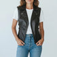Scarlett Stitch women's black faux leather motorcycle vest with lapel collar, zipper, and buckle straps. Sleeveless, form-fitting.