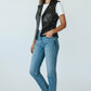 Scarlett Stitch women's black faux leather motorcycle vest with lapel collar, zipper, and buckle straps. Model wears with white t-shirt and jeans.