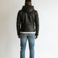 Scarlett Stitch men's black hooded leather jacket with zipper closure and zippered cuffs, worn with blue jeans.