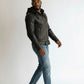 Scarlett Stitch black leather hooded jacket with zipper details and zippered cuffs, worn by a man in blue jeans.
