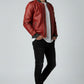 Scarlett Stitch men's red faux leather bomber jacket with ribbed cuffs and sleeve zip pocket. Model wears white tee and black jeans.