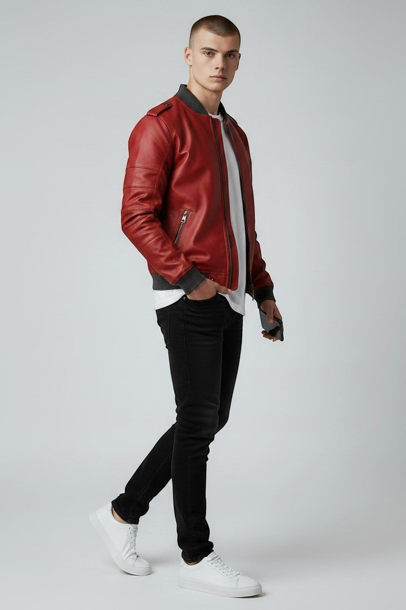 Scarlett Stitch men's red faux leather bomber jacket with ribbed cuffs and grey collar, worn by a model with black jeans and white sneakers.